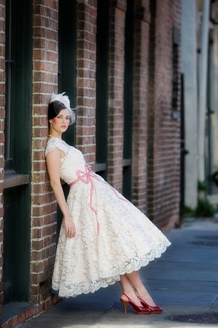Koronkowa sukienka ślubna w stylu lat 50-tych z ozdobną różową kokardą (źródło: pinterest.com)