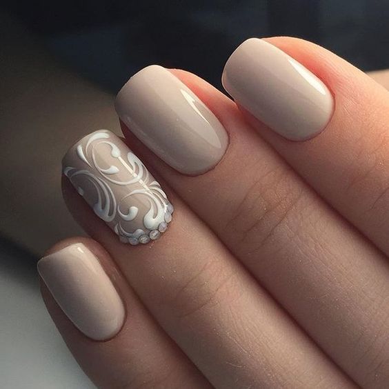 ślubny manicure w kolorze beżowym z przepięknym biały ażurem na paznokciu palca serdecznego