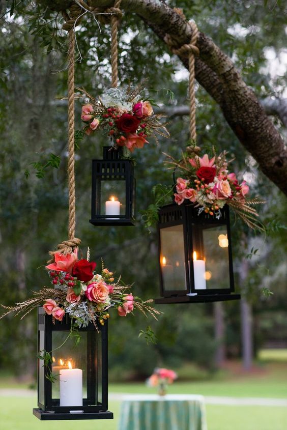 wesele w stylu rustykalnym to również przepiękne dekoracje np. lampiony podwieszone na linie na gałęzi i przybrane stroikami kwiatowymi