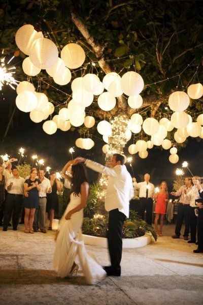 wesele pod gołym niebem pełne światła dzięki podwiesonym lampionom i zimnym ogniom trzymanych przez goźci podczas pierwszego tańca państwa młodych